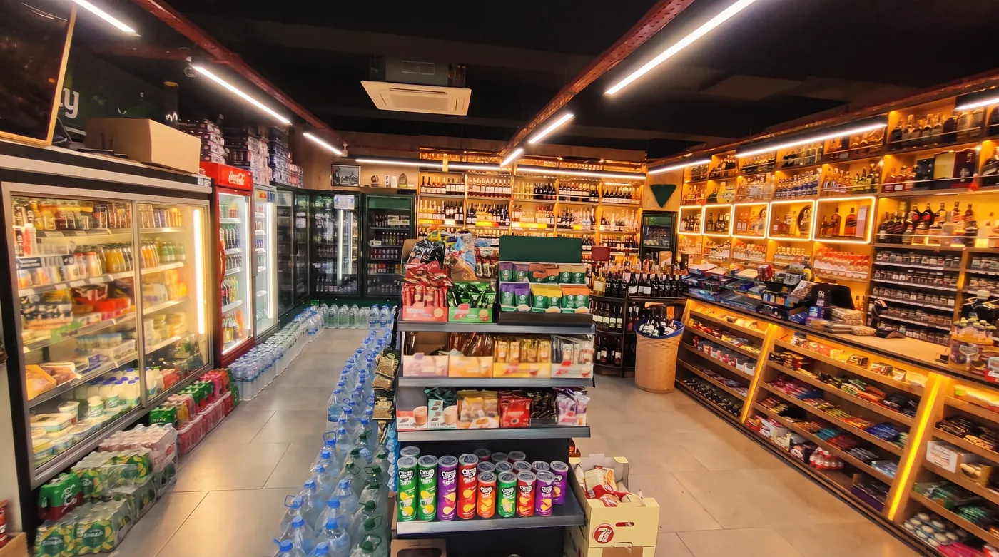 Green 216 Market’in iç mekânı: solda soğutucu dolaplar, sağda ahşap raf duvarı, ortada kahve standı